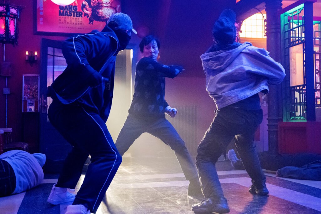 alt="Scene from 'Love Hurts' showing Ke Huy Quan in an ornate interior fighting two opponents in a fast‑paced action sequence."
