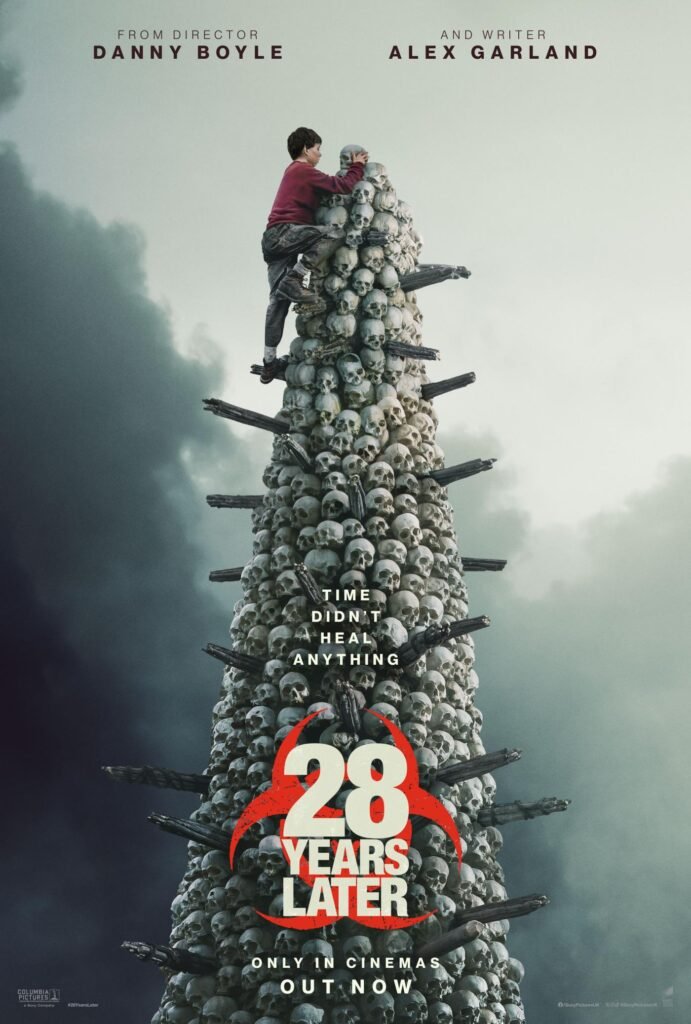 alt="Poster for the 2025 film '28 Years Later' featuring a towering structure made of skulls with rifles jutting outward and a lone figure in a red jacket climbing it against a stormy sky."
