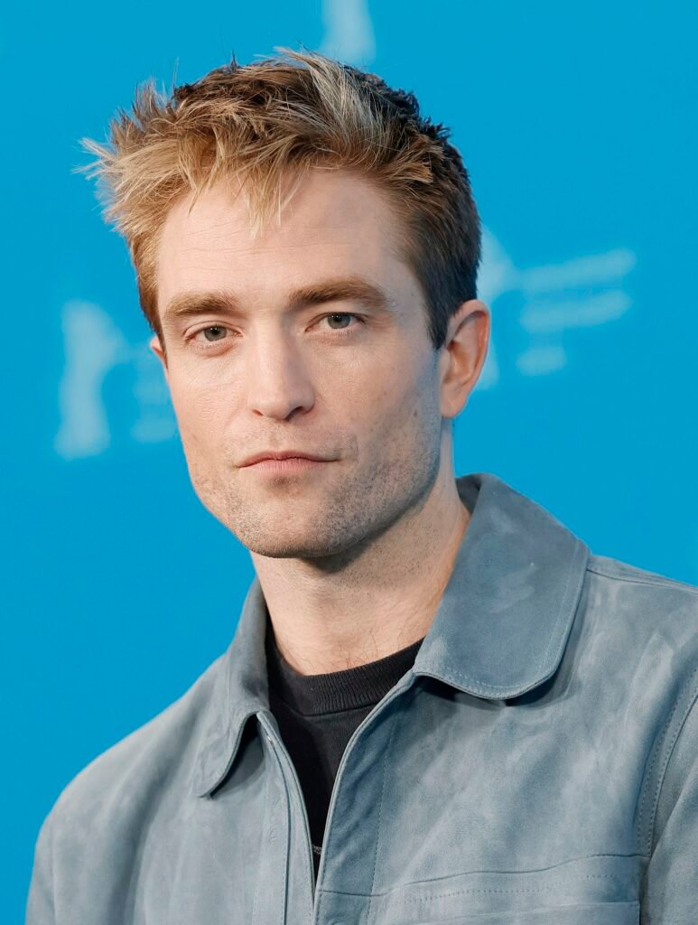 Alt="Robert Pattinson at a film event in a grey suede jacket, appearing in promotional coverage as buzz grows around the Dune Part Three teaser trailer."