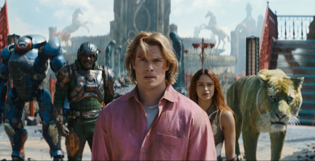 Alt = (l-r): Roboto (Kristen Wiig), Man At Arms (Idris Elba), Adam (Nicholas Galitzine), Teela (Camila Mendes) and Cringer in MASTERS OF THE UNIVERSE. Masters of the Universe © 2026 Amazon MGM Studios / Sony Pictures / Mattel.
Masters Of The Universe Review