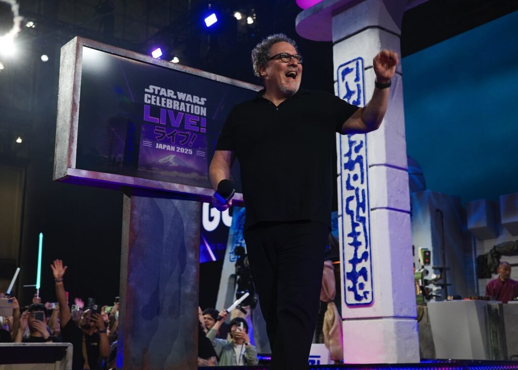 Alt = Jon Favreau walks out at a panel at the 2025 Star Wars Celebration in Japan.

Sara Komatsu

Creative Commons Attribution-Share Alike 4.0
Star Wars: The Mandalorian And Grogu Review