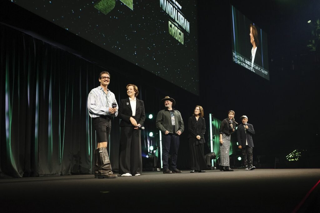 Alt = Mandalorian and Grogu panel at the 2025 Star Wars Celebration in Japan, including speakers like Pedro Pascal, Sigourney Weaver, Dave Filoni, and more.

Sara Komatsu

Creative Commons Attribution-Share Alike 4.0
Star Wars: The Mandalorian And Grogu Review
